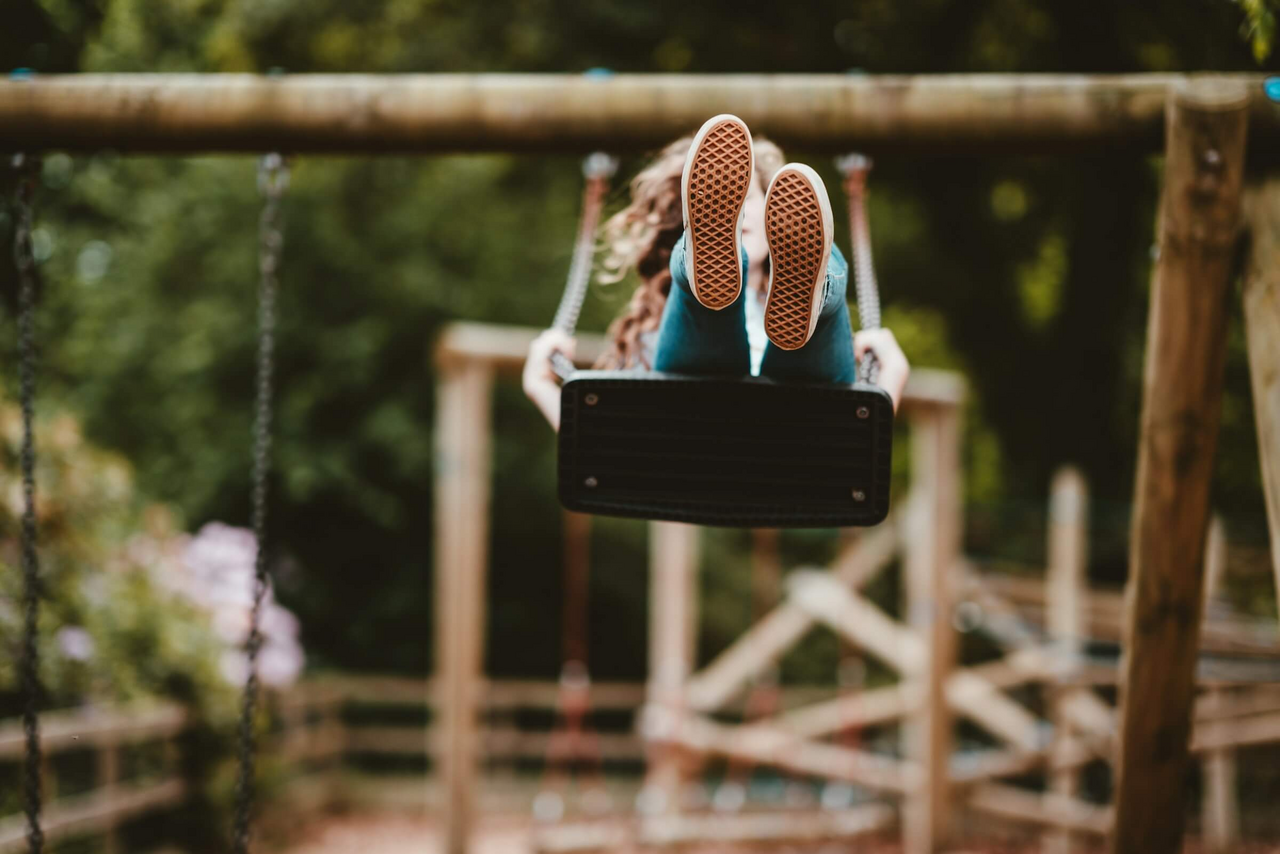 Frau schaukelt auf Spielplatz.